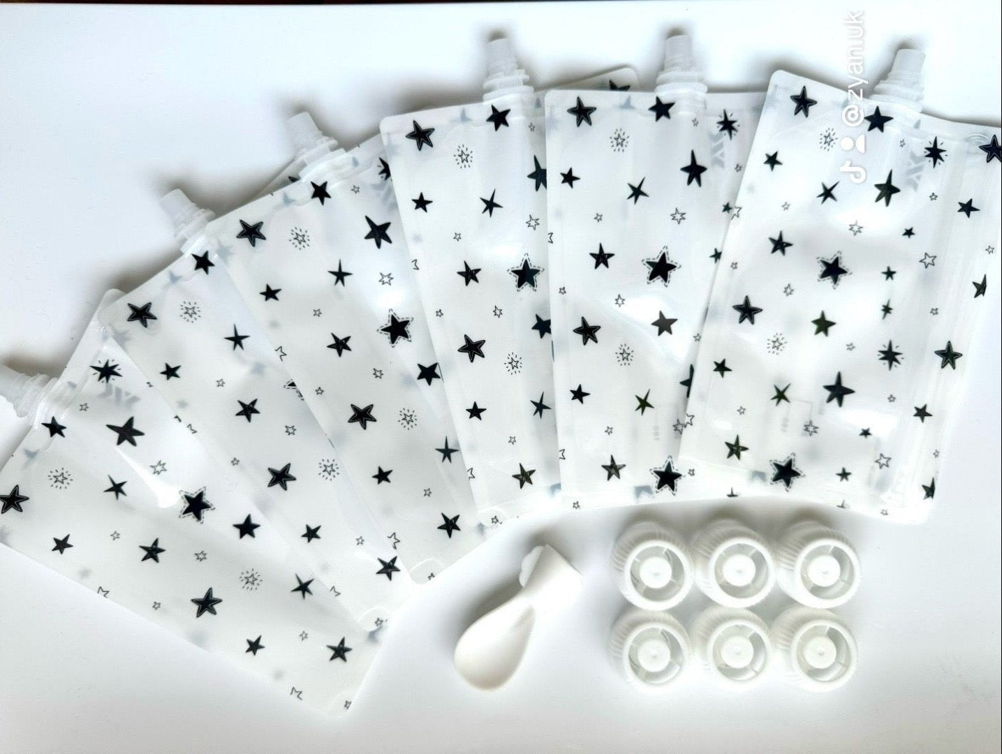 Reusable food pouches for babies and toddlers with star patterns, featuring six pouches, six caps, and a spoon-tip, perfect for purees and snacks.