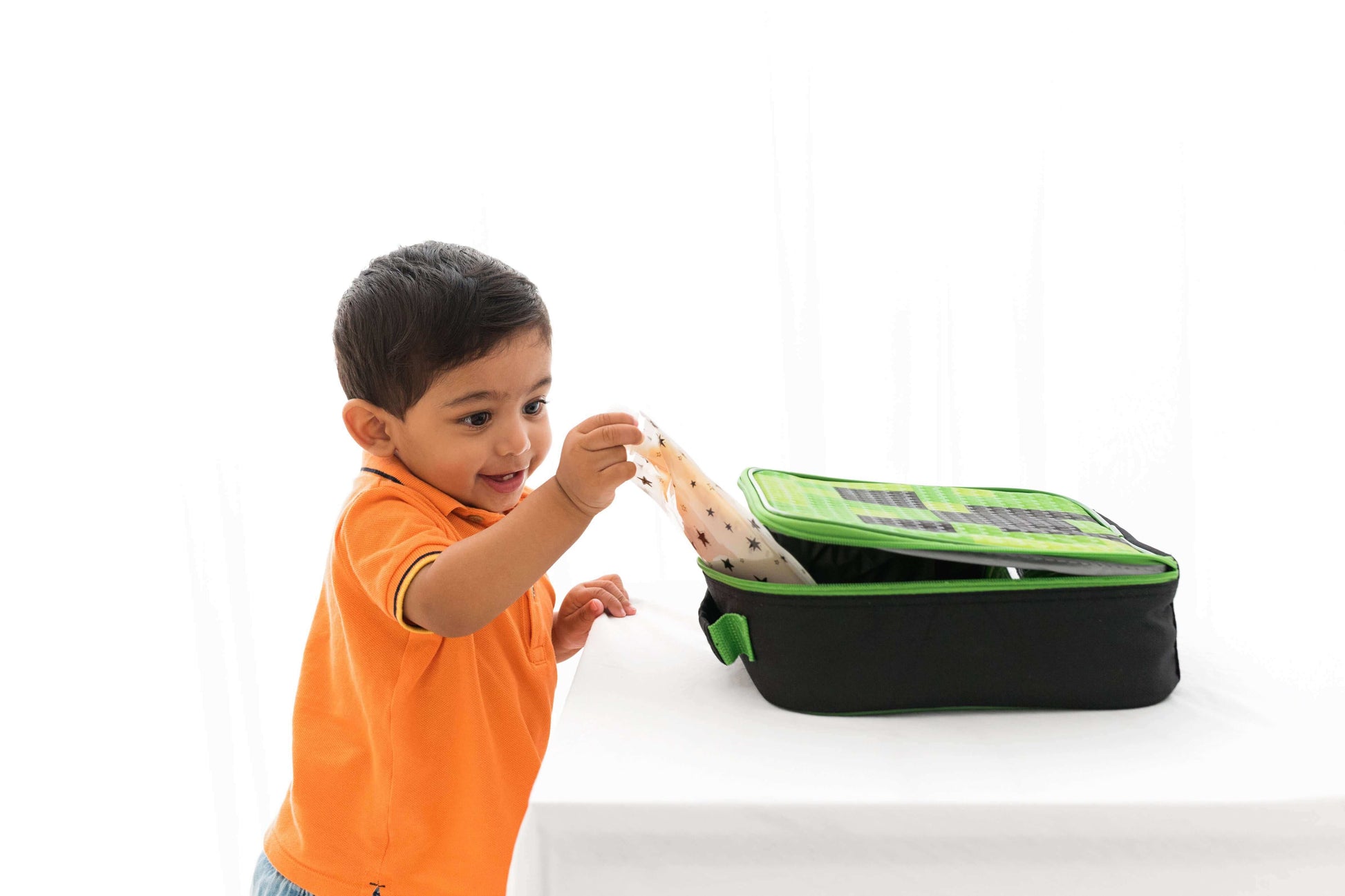 Toddler using a reusable food pouch from a green lunch bag, showcasing weaning essentials and convenience for babies on the go.