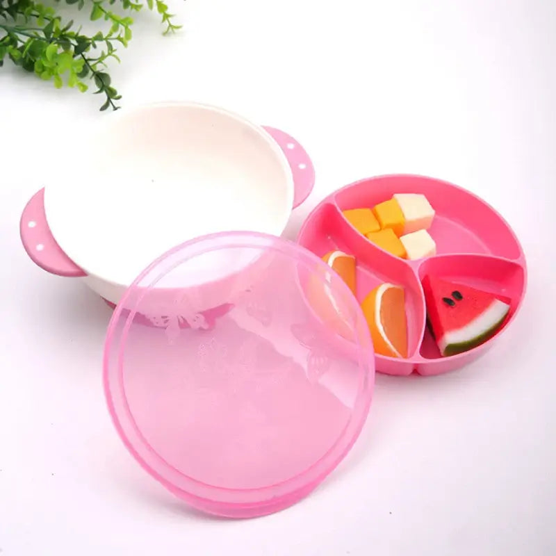 Suction bowls for babies featuring a pink divided plate with assorted fruits and a white bowl with handles.